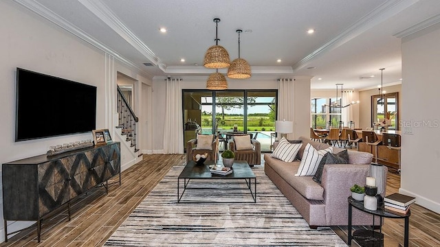 living room featuring a raised ceiling, a notable chandelier, and ornamental molding