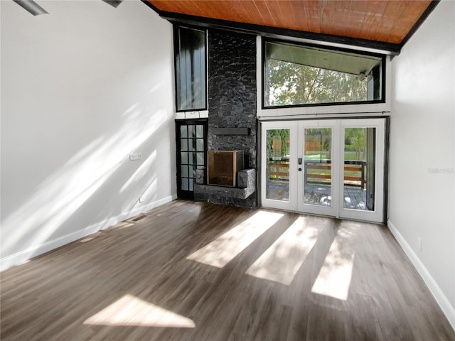 unfurnished living room featuring french doors, a towering ceiling, a fireplace, and wood-type flooring