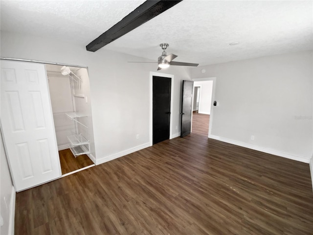 unfurnished bedroom with a textured ceiling, beamed ceiling, ceiling fan, a closet, and dark hardwood / wood-style flooring