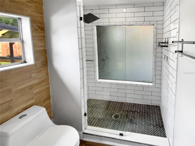 bathroom featuring toilet, tiled shower, and plenty of natural light