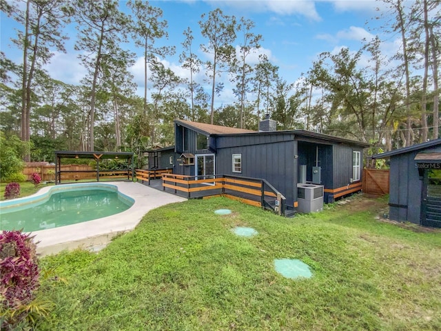 rear view of property with a swimming pool side deck, central air condition unit, and a yard