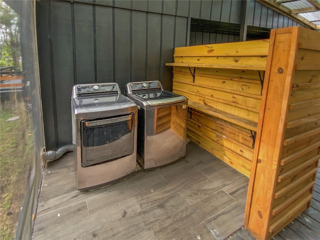 clothes washing area with wood walls and washing machine and clothes dryer