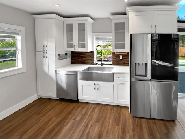 kitchen with dark wood-type flooring, stainless steel appliances, decorative backsplash, white cabinets, and sink