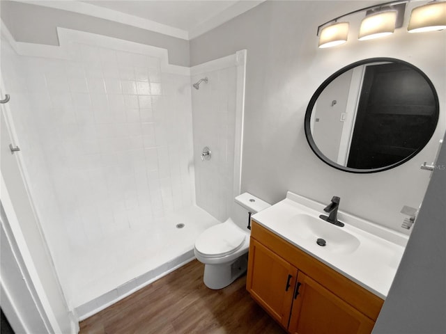 bathroom with ornamental molding, hardwood / wood-style flooring, toilet, walk in shower, and vanity