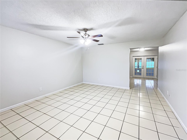 empty room featuring ceiling fan, a textured ceiling, light tile patterned flooring, and french doors