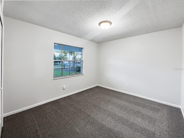 unfurnished room featuring a textured ceiling and dark colored carpet