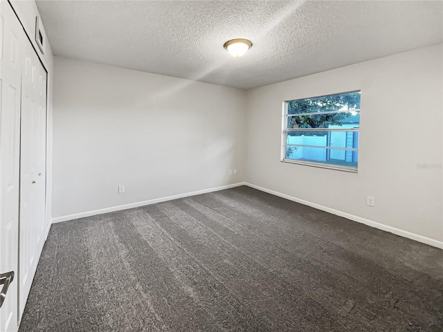 unfurnished bedroom featuring a closet, a textured ceiling, and dark colored carpet