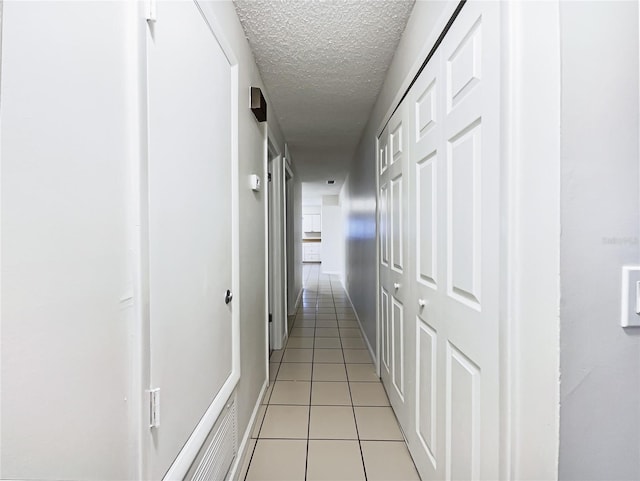 hall featuring light tile patterned flooring and a textured ceiling