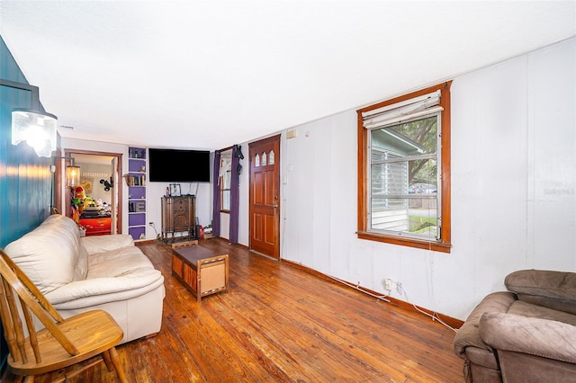 living room featuring built in shelves and hardwood / wood-style flooring