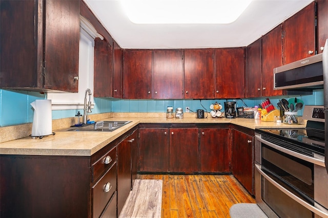 kitchen with appliances with stainless steel finishes, light hardwood / wood-style floors, and sink