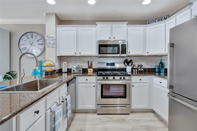 kitchen featuring sink, white cabinets, stainless steel appliances, and dark stone counters