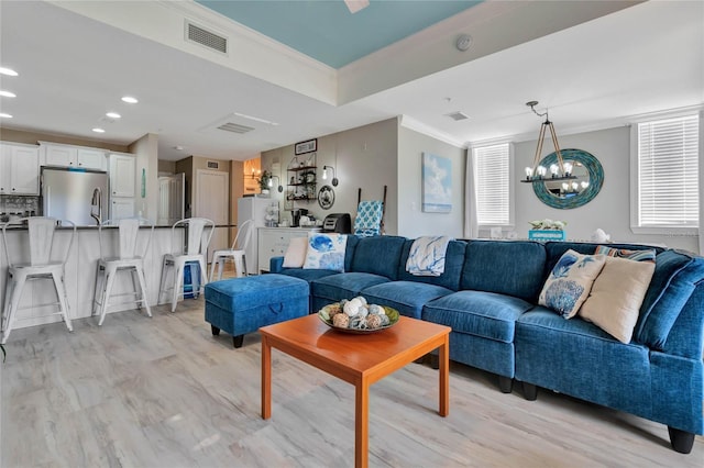 living room with light hardwood / wood-style floors, ornamental molding, a notable chandelier, and a healthy amount of sunlight