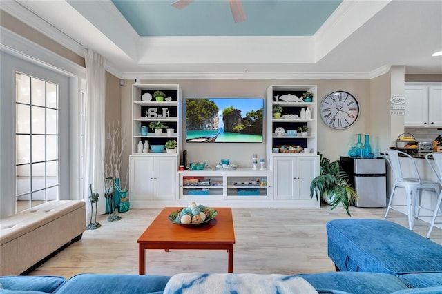 living room featuring a wealth of natural light, light hardwood / wood-style floors, and a tray ceiling