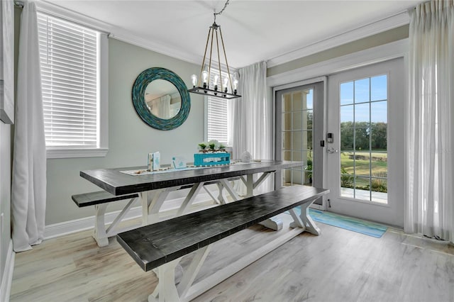 dining space with french doors, an inviting chandelier, ornamental molding, and light hardwood / wood-style flooring