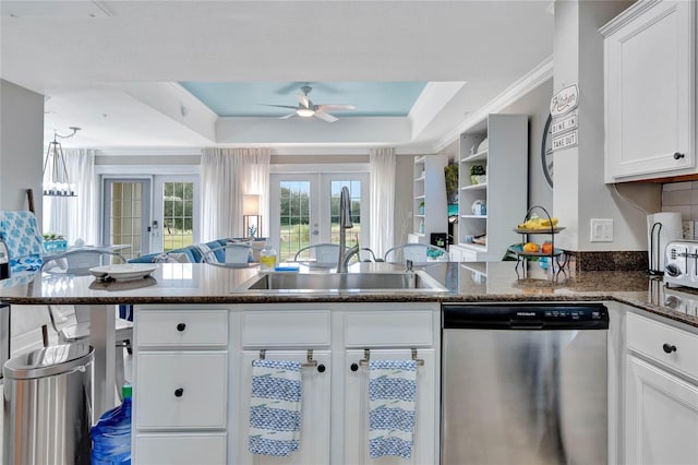 kitchen featuring ceiling fan, stainless steel dishwasher, a tray ceiling, white cabinetry, and french doors