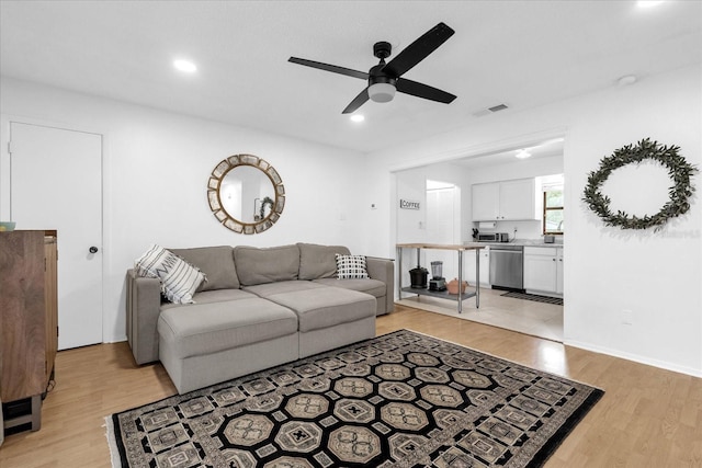 living room with ceiling fan and light hardwood / wood-style flooring