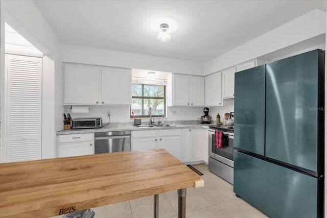 kitchen with sink, white cabinets, light tile patterned flooring, and appliances with stainless steel finishes