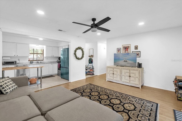 living room with ceiling fan, light hardwood / wood-style flooring, and sink