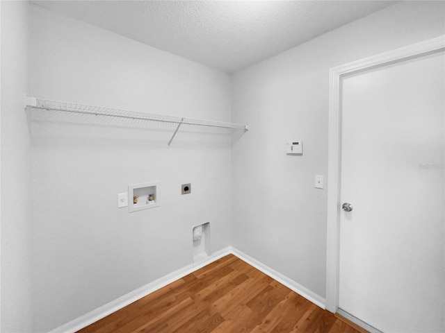 washroom with a textured ceiling, hookup for an electric dryer, wood-type flooring, and washer hookup