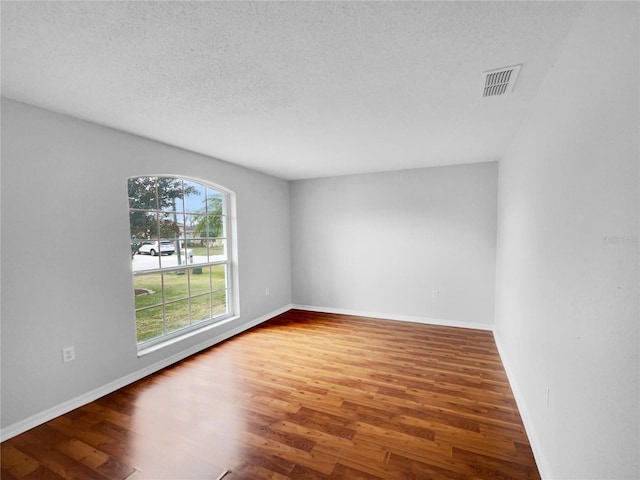 spare room featuring wood-type flooring and a textured ceiling