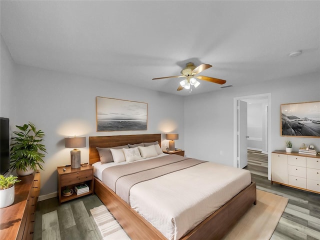 bedroom featuring ceiling fan, dark hardwood / wood-style flooring, and connected bathroom