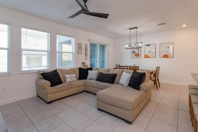 living room with ceiling fan with notable chandelier and light tile patterned floors