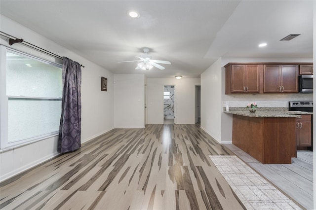 kitchen with ceiling fan, backsplash, light wood-type flooring, light stone countertops, and stainless steel appliances