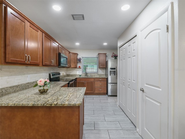 kitchen with stainless steel appliances, tasteful backsplash, sink, kitchen peninsula, and light stone counters