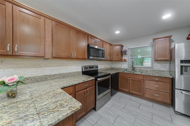 kitchen with sink, light stone counters, decorative backsplash, and stainless steel appliances