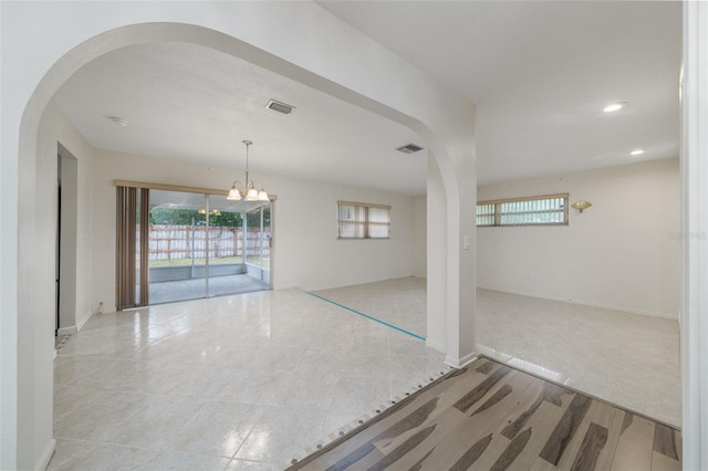 empty room with a chandelier and plenty of natural light