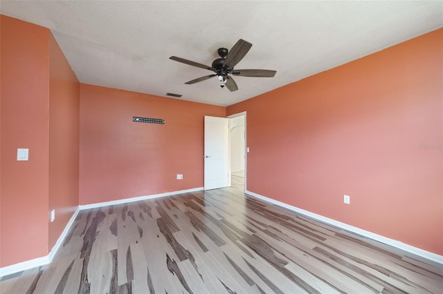 empty room with ceiling fan, a textured ceiling, and light wood-type flooring