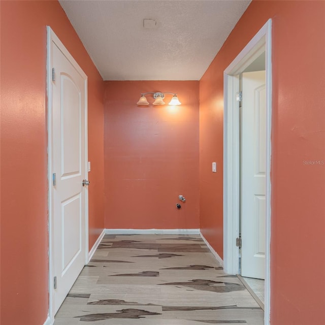 hallway with light wood-type flooring and a textured ceiling