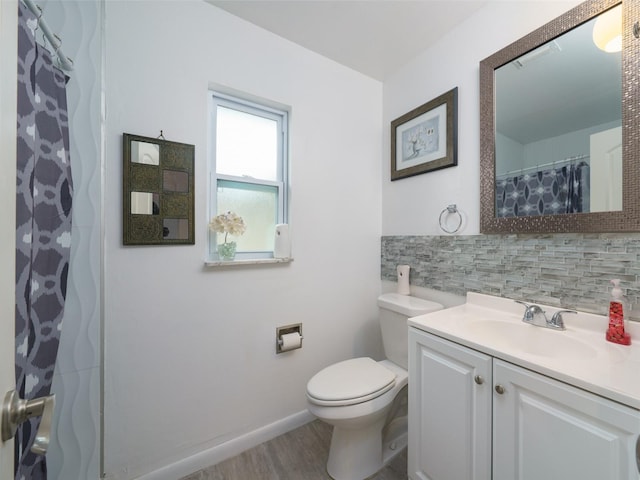 bathroom featuring toilet, hardwood / wood-style floors, decorative backsplash, and vanity