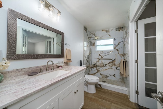 bathroom featuring toilet, tiled shower, hardwood / wood-style flooring, and vanity