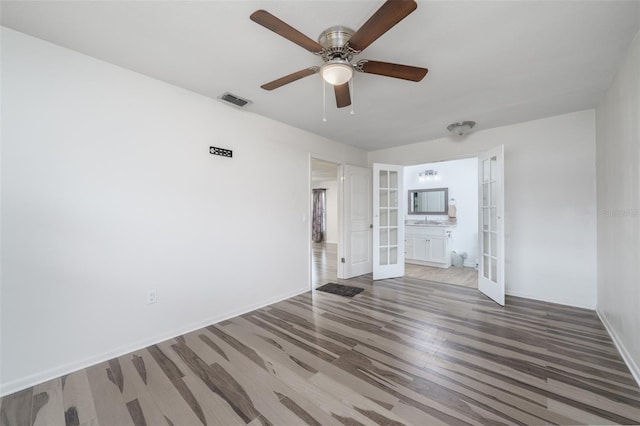 empty room with sink, hardwood / wood-style flooring, ceiling fan, and french doors