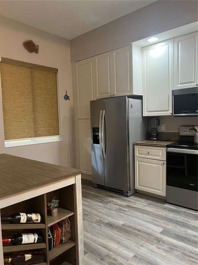 kitchen featuring stainless steel appliances, light hardwood / wood-style floors, and white cabinetry