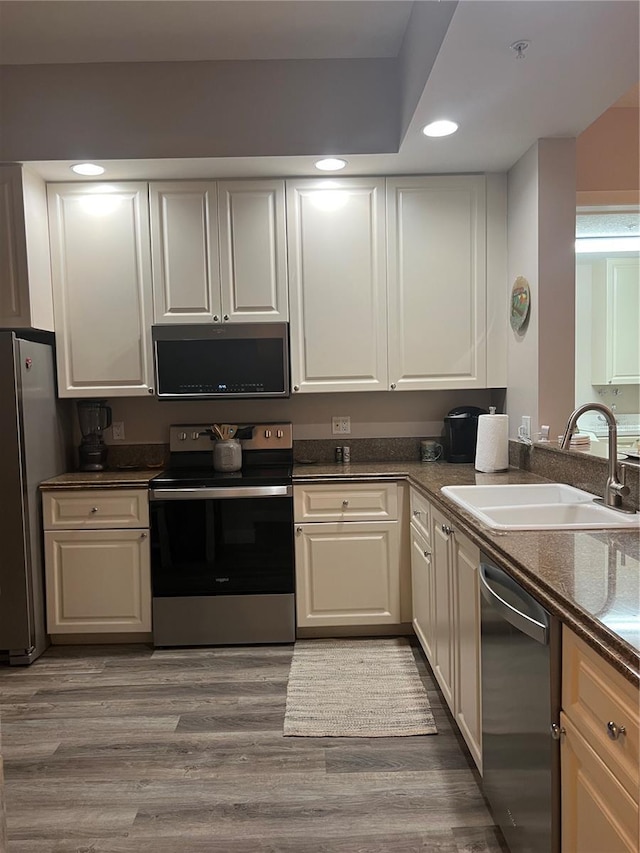 kitchen with white cabinetry, sink, wood-type flooring, and stainless steel appliances