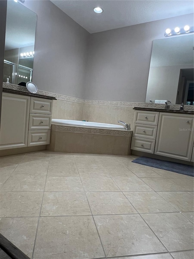 bathroom with tiled bath, tile patterned floors, and vanity