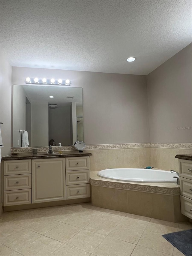 bathroom featuring a relaxing tiled tub, a textured ceiling, vanity, and tile patterned flooring