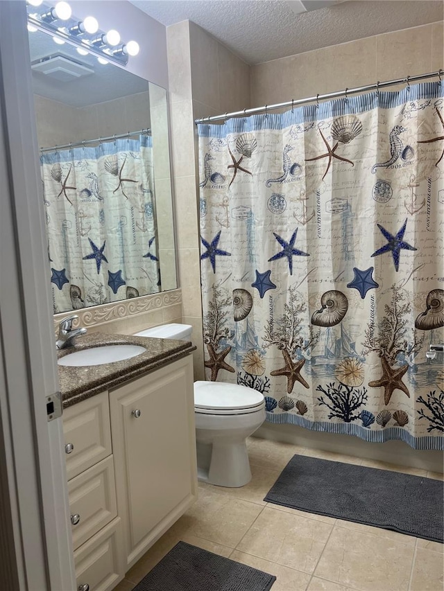 bathroom featuring walk in shower, vanity, toilet, tile patterned floors, and a textured ceiling