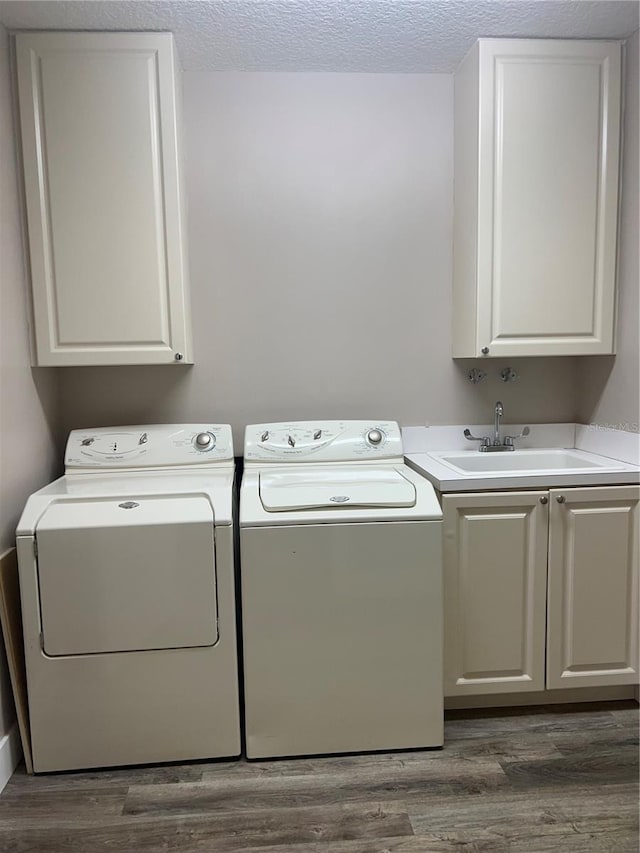 laundry room with a textured ceiling, sink, washing machine and clothes dryer, and cabinets