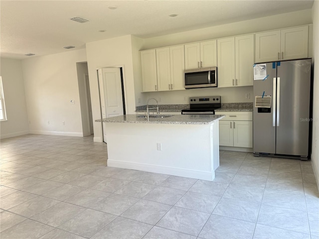 kitchen featuring light stone countertops, an island with sink, white cabinetry, appliances with stainless steel finishes, and sink