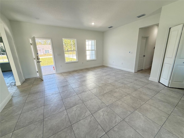 tiled empty room featuring a textured ceiling