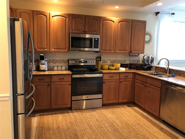 kitchen featuring backsplash, appliances with stainless steel finishes, sink, and dark stone countertops