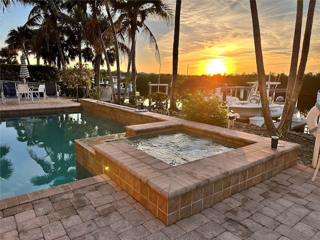 view of dock with a patio area and an in ground hot tub