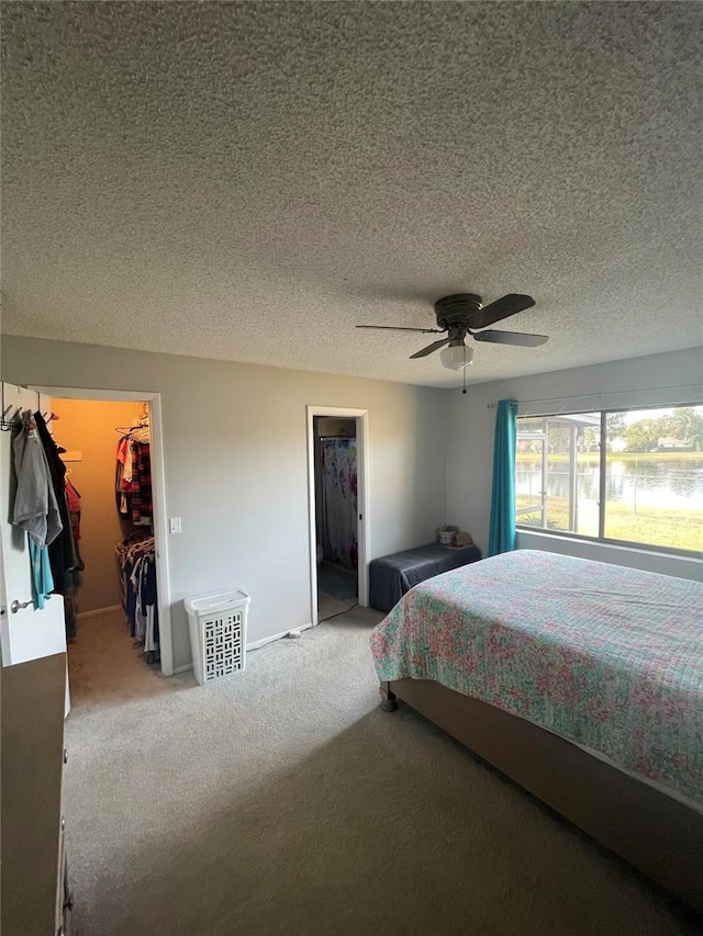 carpeted bedroom with a spacious closet, ceiling fan, and a closet