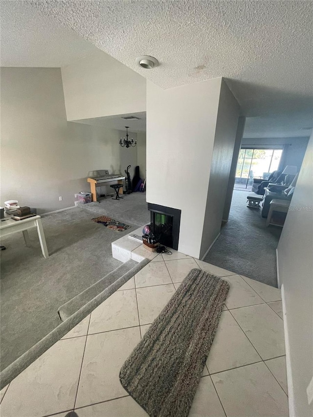 hall featuring carpet, vaulted ceiling, a textured ceiling, and tile patterned floors