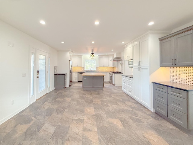 kitchen featuring appliances with stainless steel finishes, tasteful backsplash, wall chimney exhaust hood, gray cabinets, and a kitchen island