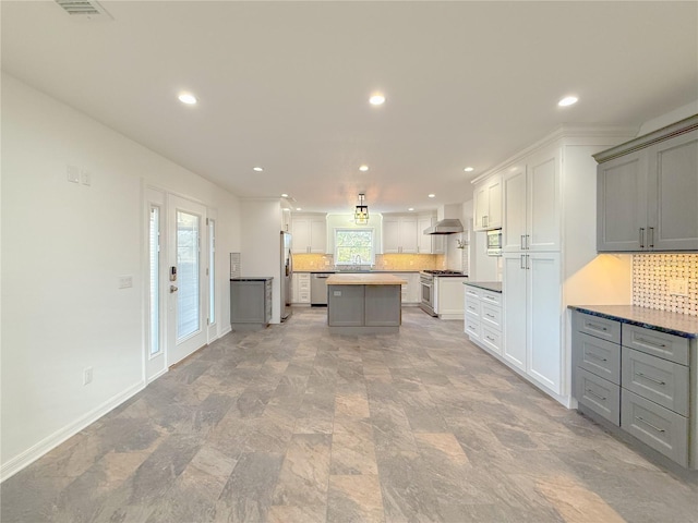 kitchen featuring gray cabinetry, decorative backsplash, a center island, and appliances with stainless steel finishes