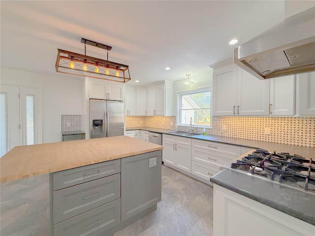 kitchen featuring appliances with stainless steel finishes, white cabinetry, extractor fan, and sink